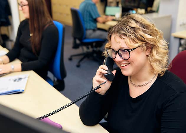 A woman in an office, talking on the telephone.