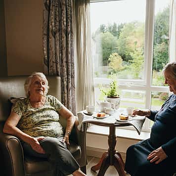 Two elderly women enjoying tea and cake over a candid conversation