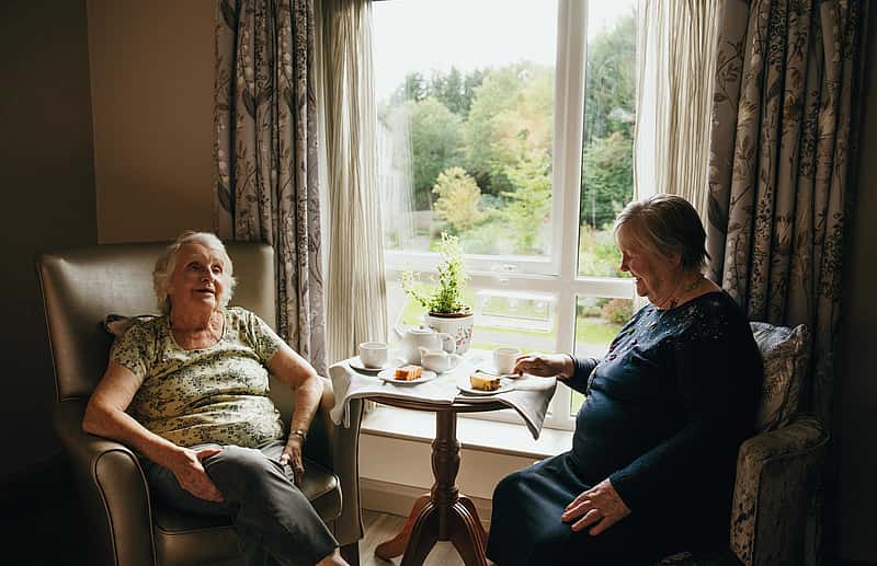Two elderly women enjoying tea and cake over a candid conversation