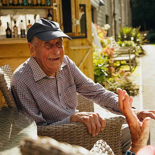 An elderly man, smiling and enjoying a candid conversation