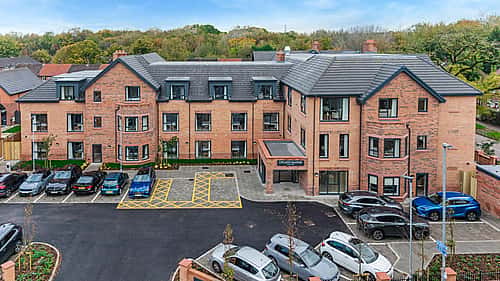 A modern residential building with a well-maintained parking area and surrounding greenery.