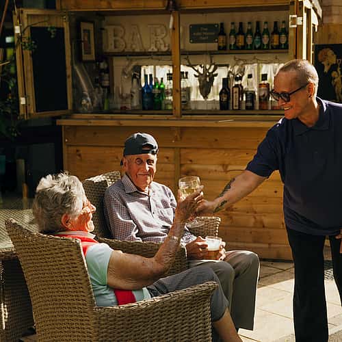 A bar tender serving drinks to elderly inviduals