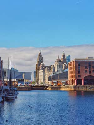 The historic Albert Dock in Merseyside, with its red brick warehouses and the iconic Liver Building in the background.