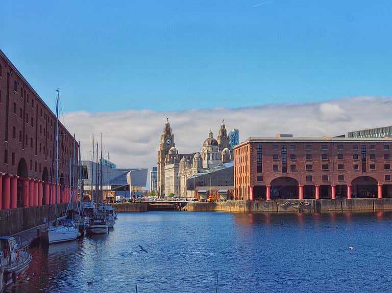 The historic Albert Dock in Merseyside, with its red brick warehouses and the iconic Liver Building in the background.