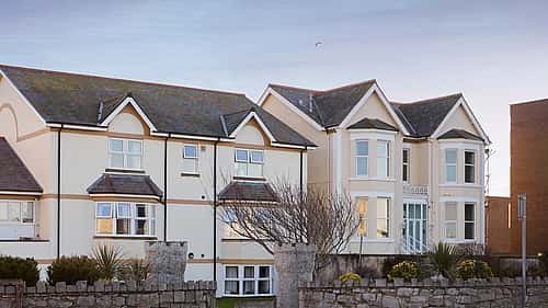 A row of two-story buildings with traditional architecture and a stone wall in the foreground.