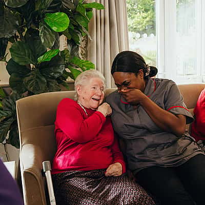 An elderly woman conversing with a care professional enjoying a laugh