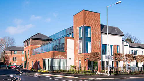A modern brick building with large glass windows and a contemporary design located at a street corner.
