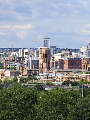 A vibrant skyline of Leeds, featuring modern high-rise buildings and green surroundings.
