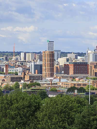 A vibrant skyline of Leeds, featuring modern high-rise buildings and green surroundings.