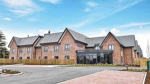A modern brick building with a reception area in the front and a neatly paved parking lot.