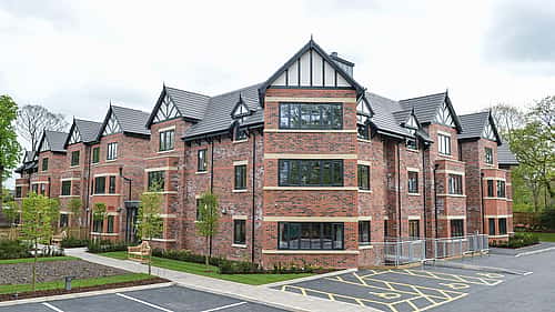 A modern brick apartment building with large windows and neatly landscaped surroundings.
