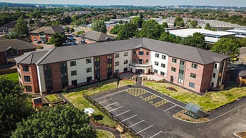 A modern, three-story building with a spacious parking lot and neatly landscaped grounds.