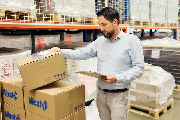 A man with a clipboard inspecting an order prior to shipping.
