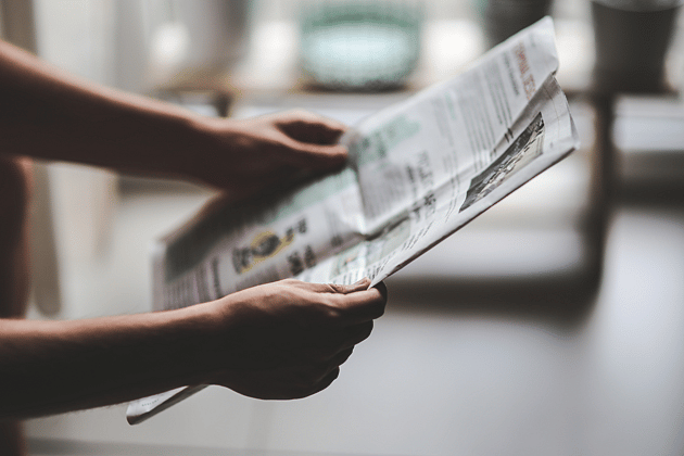 News Pair of hands holding a newspaer reading