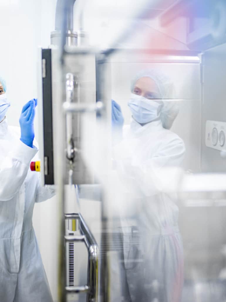 A woman in protective clothing in front of an isolator.