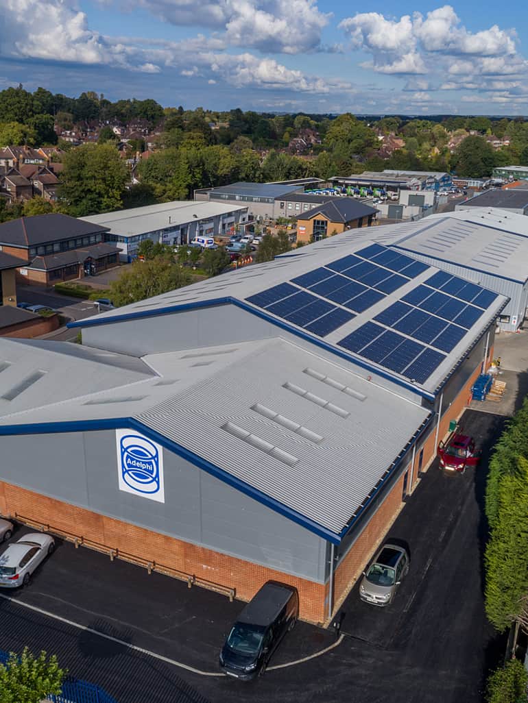 Luftaufnahme der Adelphi Büro- und Lagergebäude, umgeben von Sträuchern und Bäumen sowie einem blauen Himmel mit leichten Wolken.