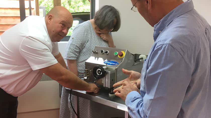 two men and one woman lean over a Response Benchtop filler