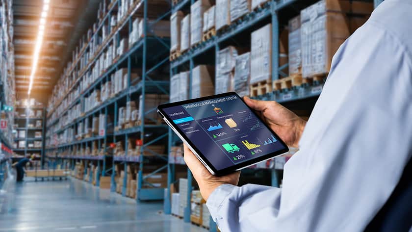 An image of someone holding an iPad in a warehouse.