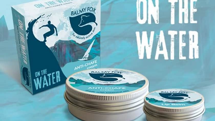 on a blue geometric background is a Balmy Fox product with a blue box and a large and small tin of balm, with blue labels on