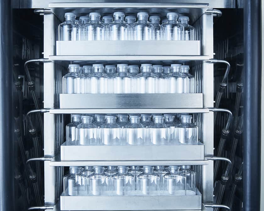 Freeze dryer shelves filled with stoppered vials.