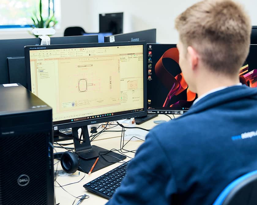 Adelphi 0351 Person sitting at PC looking at tech drawings