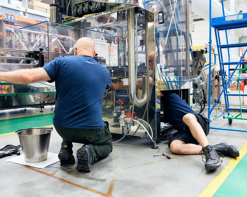 Adelphi 0525 Two peple working on machine toegther fitting parts