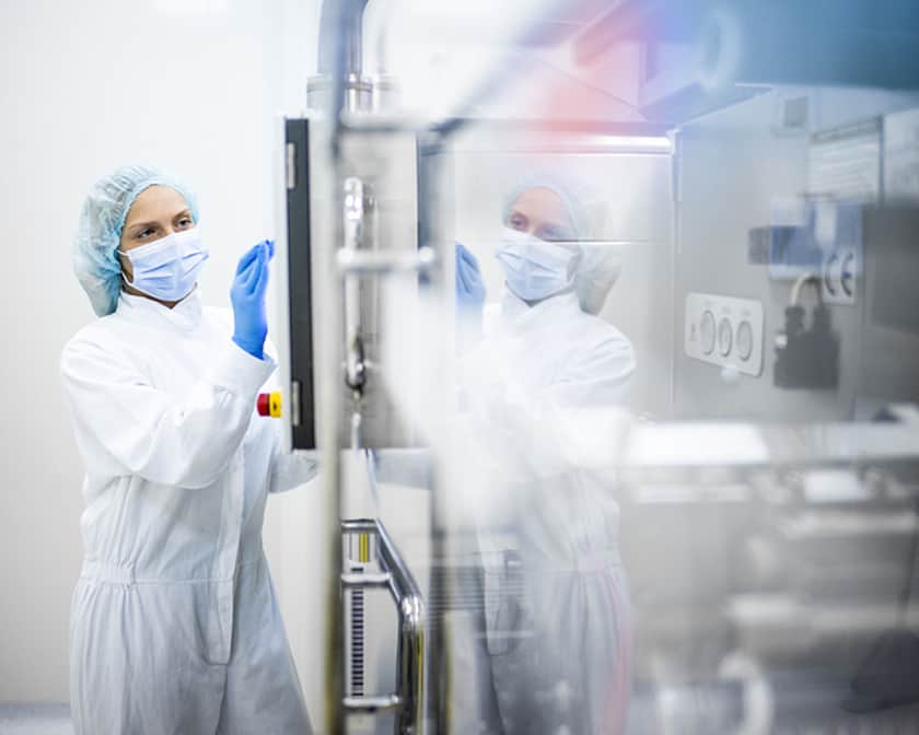An image of a lady wearing protective gear in front of a machine.