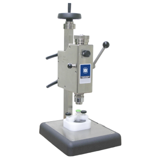 Close-up of precision laboratory bench crimper machine used for sealing glass vials in pharmaceutical and industrial quality control applications