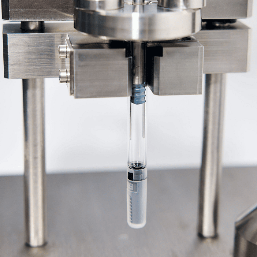 Close-up of precision laboratory equipment holding a glass vial during automated quality control testing in a controlled environment
