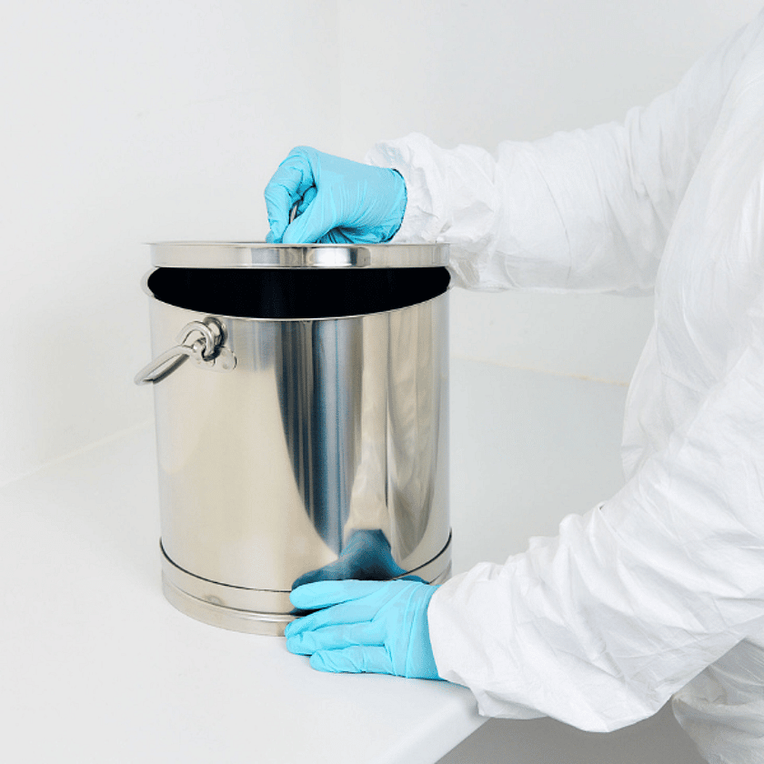Gloved hands securing the lid of a stainless steel mixing container in a clean environment, highlighting hygienic handling, pharmaceutical or cosmetic formulation, and controlled processing conditions.