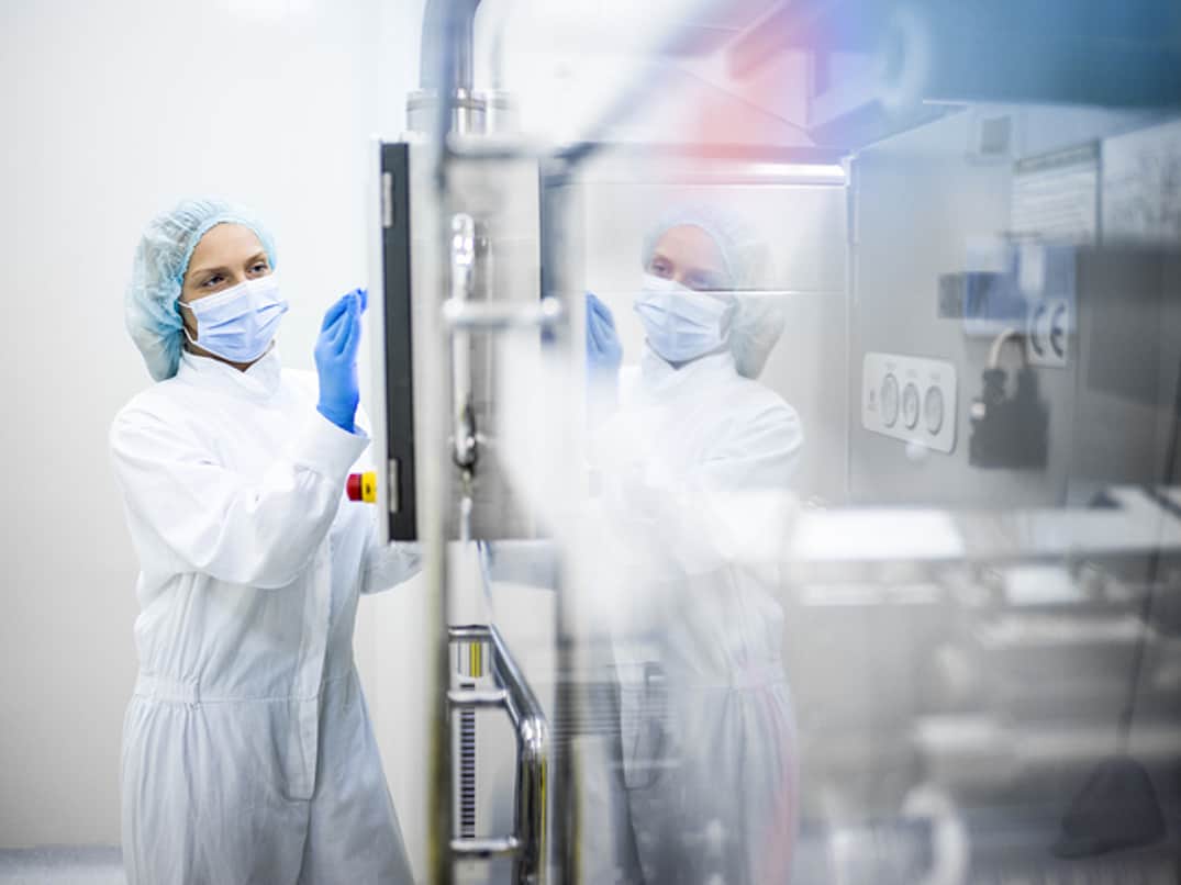 A lady in protective gear in front of a machine.