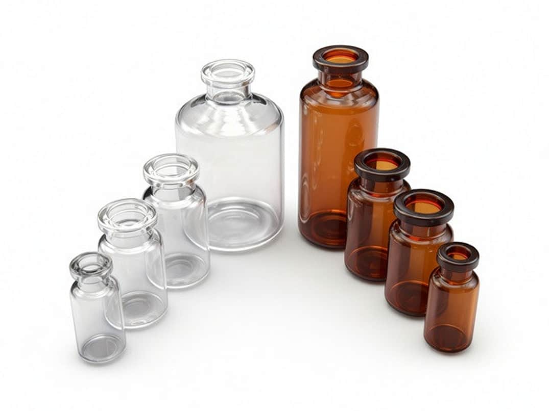 A selection of clear and amber tubular glass injection vials of differing sizes.