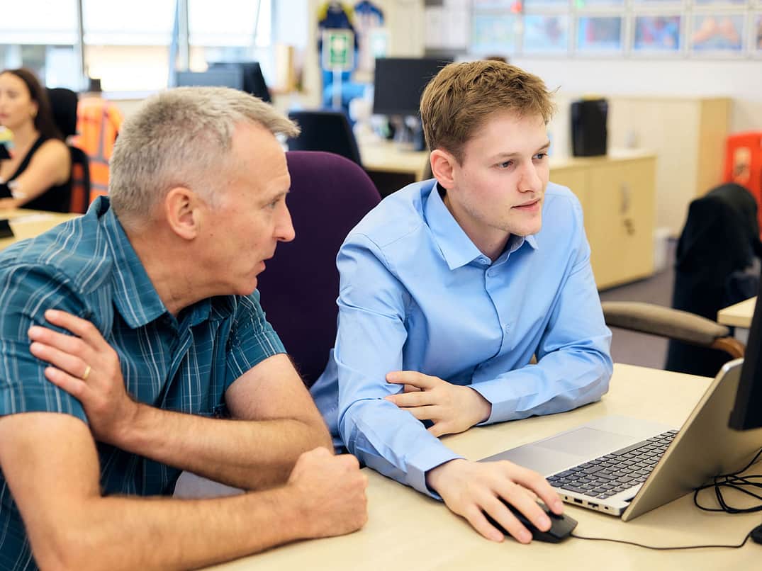Adelphi 0265 Two People infornt of a PC discussing work on a screen apprentice