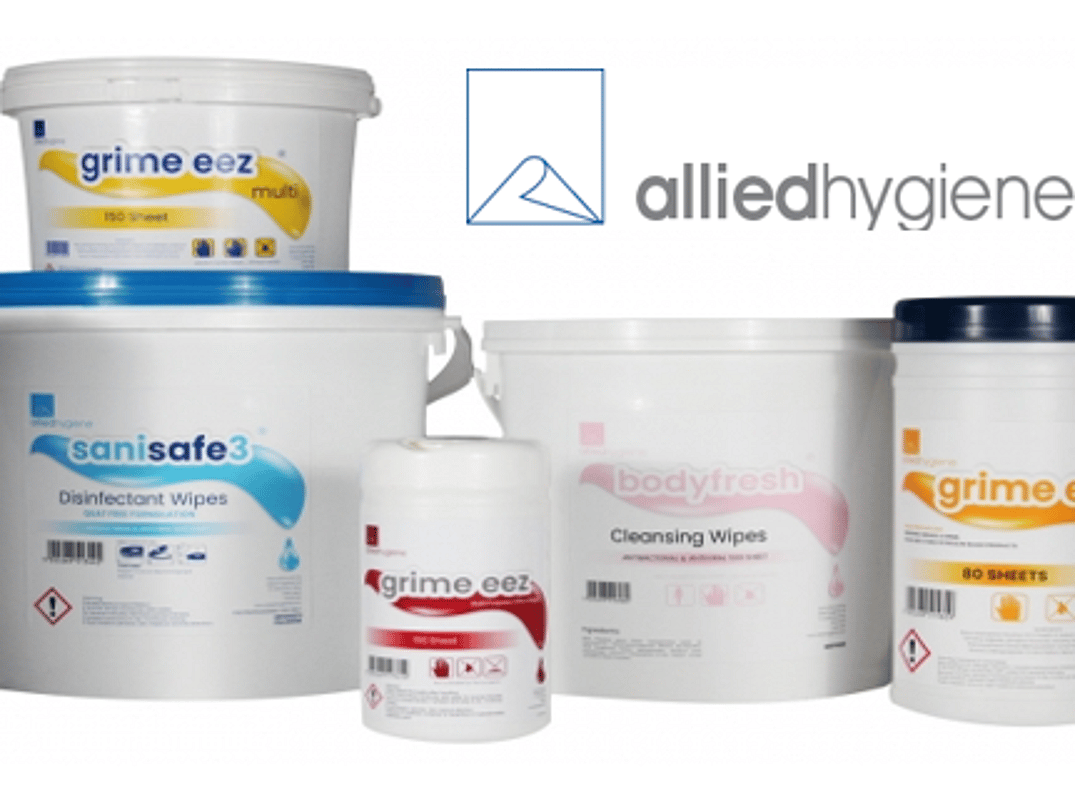Several white plastic tubs and canisters of hygiene wipes are arranged in a product display beneath the Allied Hygiene logo. Products include disinfectant wipes, cleansing wipes, and multi-purpose cleaning wipes in various container sizes with blue, pink, yellow, and red label accents. The packaging is shown on a white background for a clean, professional product presentation.