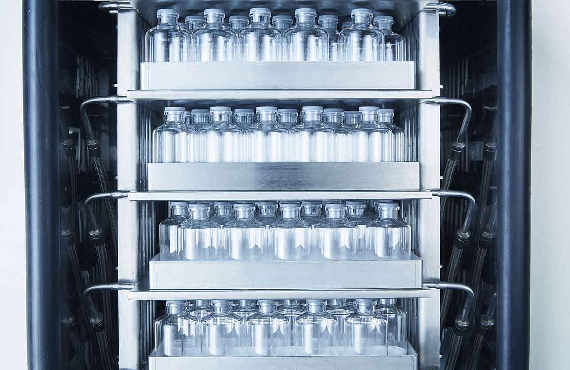 Freeze dryer shelves filled with stoppered vials.