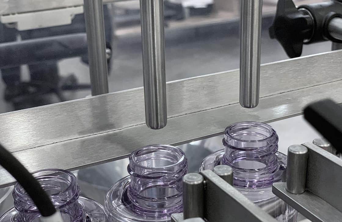 the top of the glass bottles and a filler nozzle above.