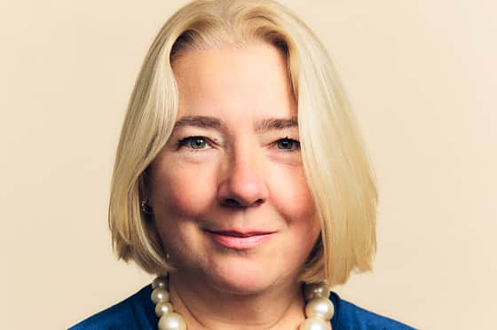 A woman with chin length blond hair, wearing a blue velvet dress.