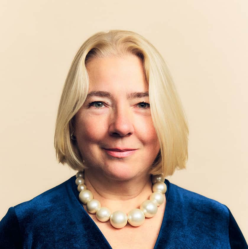 A woman with chin length blond hair, wearing a blue velvet dress.